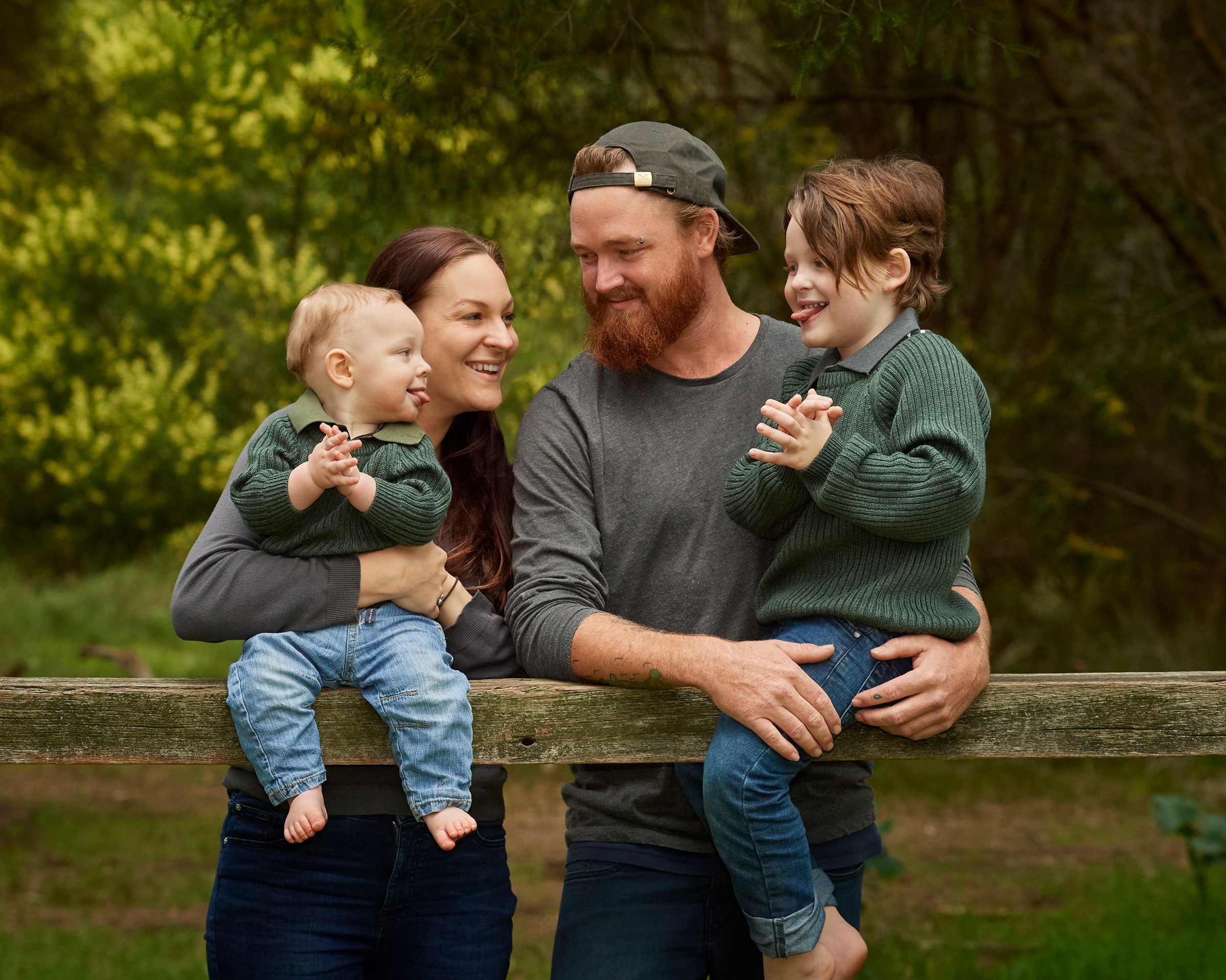 Parents and their two boys at the fence rail under the trees