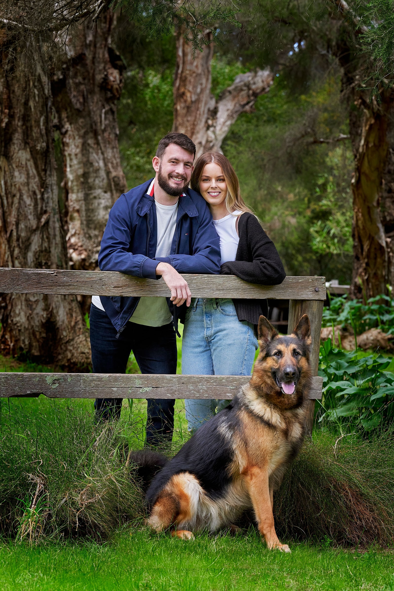 A couple at the farm fence with their German shepherd