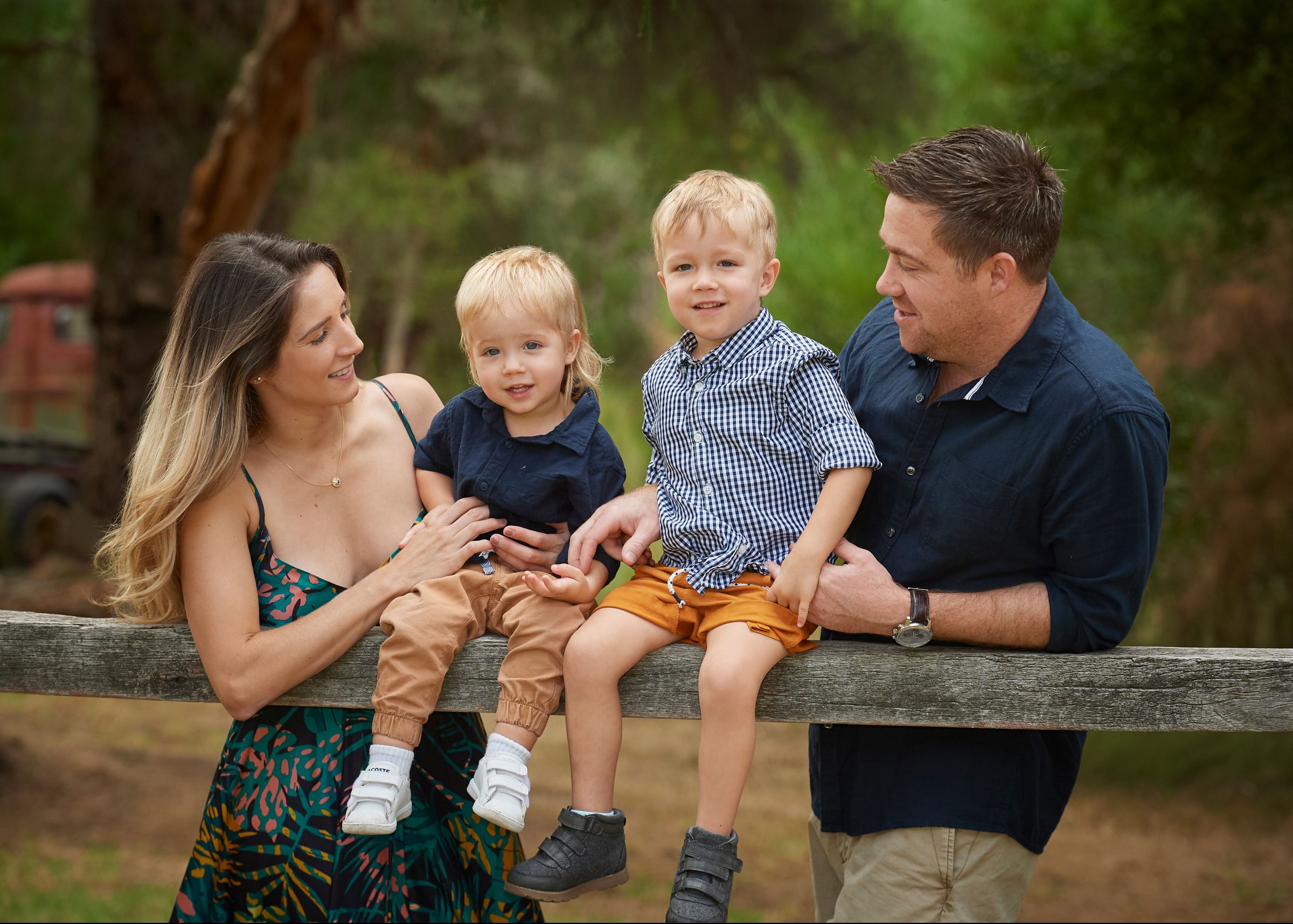 Parents with their two young boys sitting on the farm fence