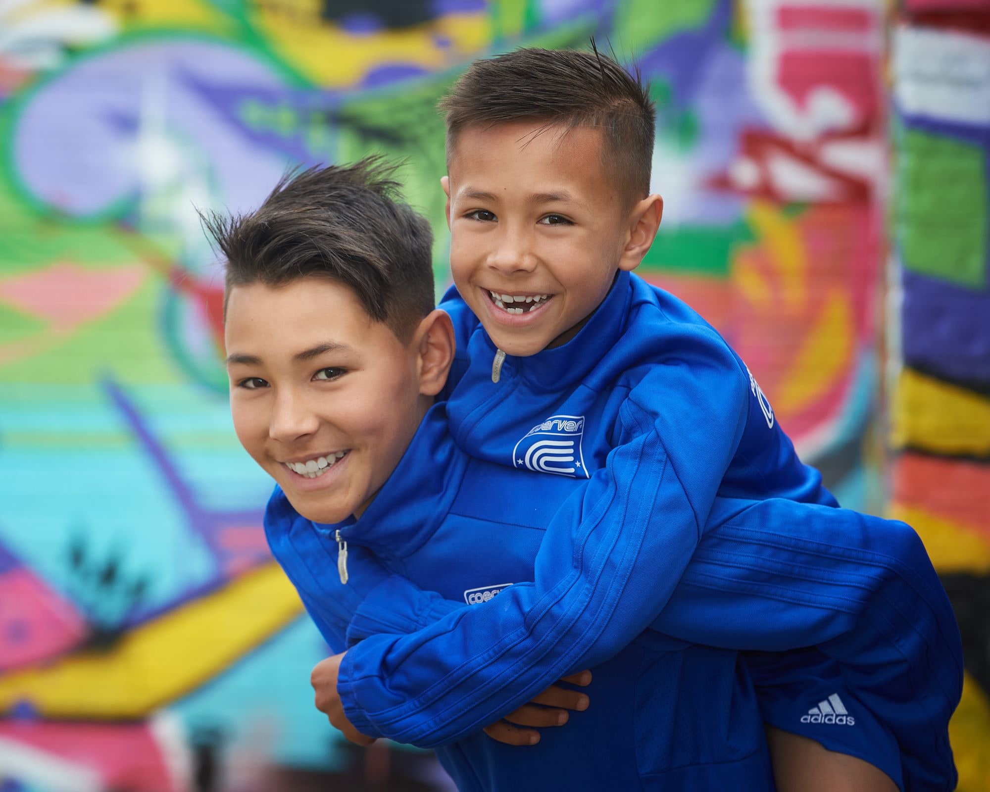 Two brothers laughing in front of the graffiti wall