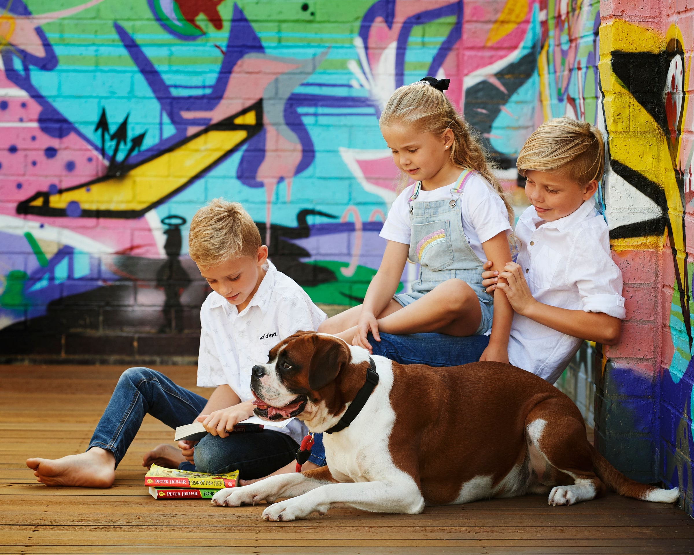 Three children and their dog sitting in front of the graffiti