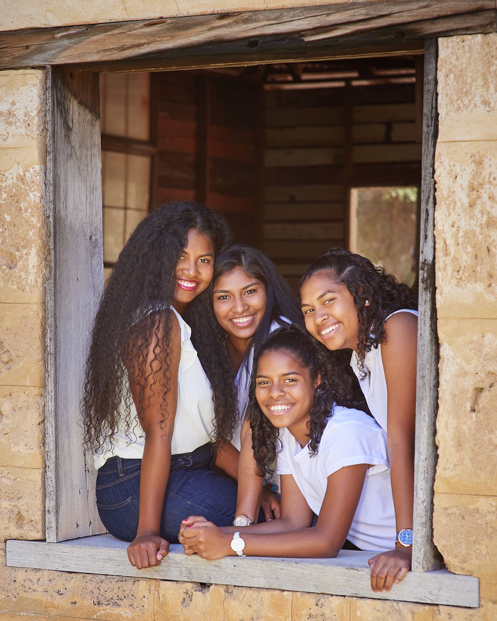Four sisters leaning out of the limestone window