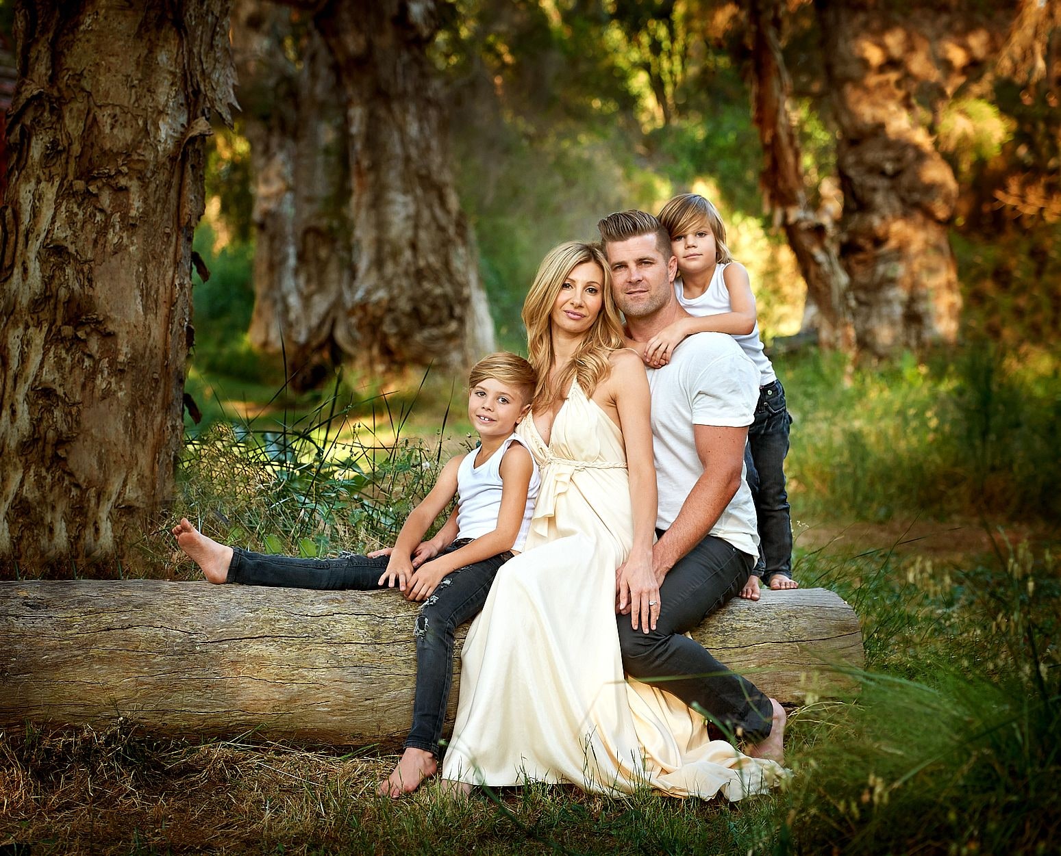 A family relaxing together on a fallen log under the paperbarks