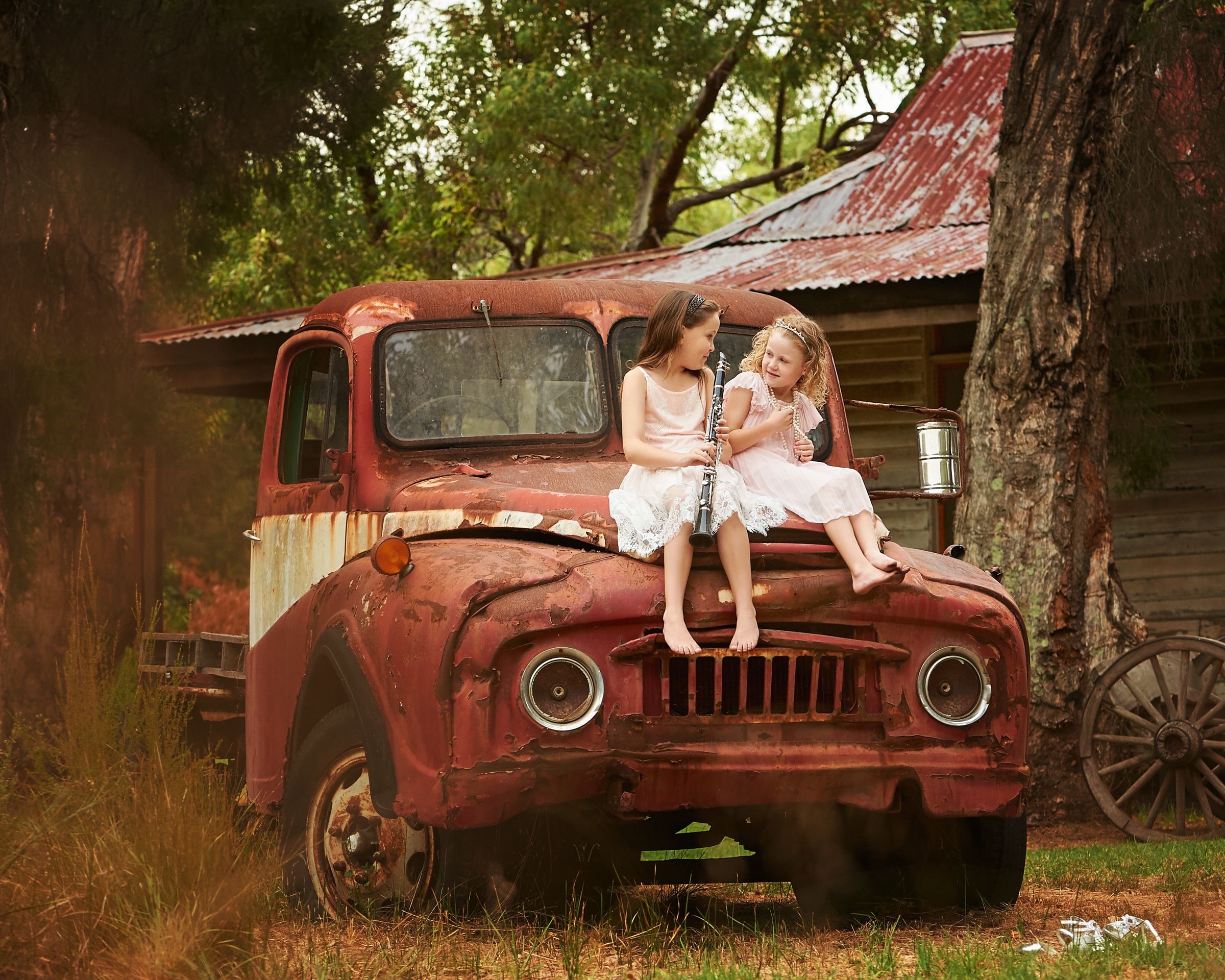 Two little sisters on the bonnet of the vintage red truck