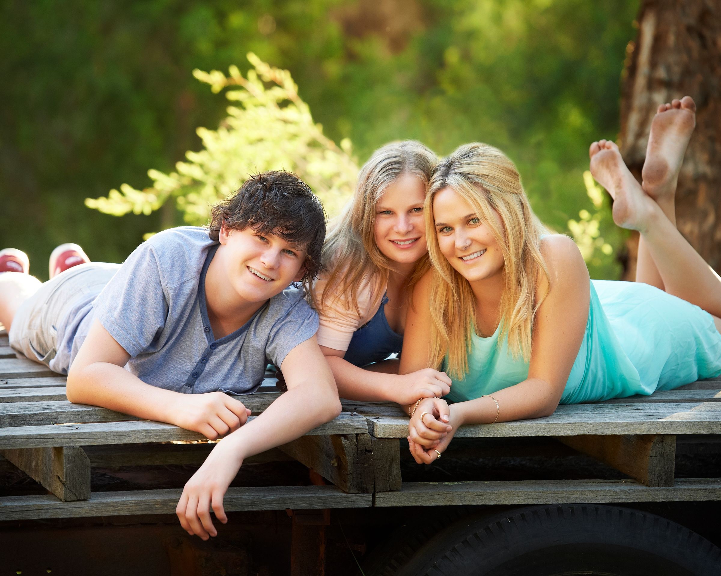 Three teenagers lying side by side on the wooden tray of a vintage truck