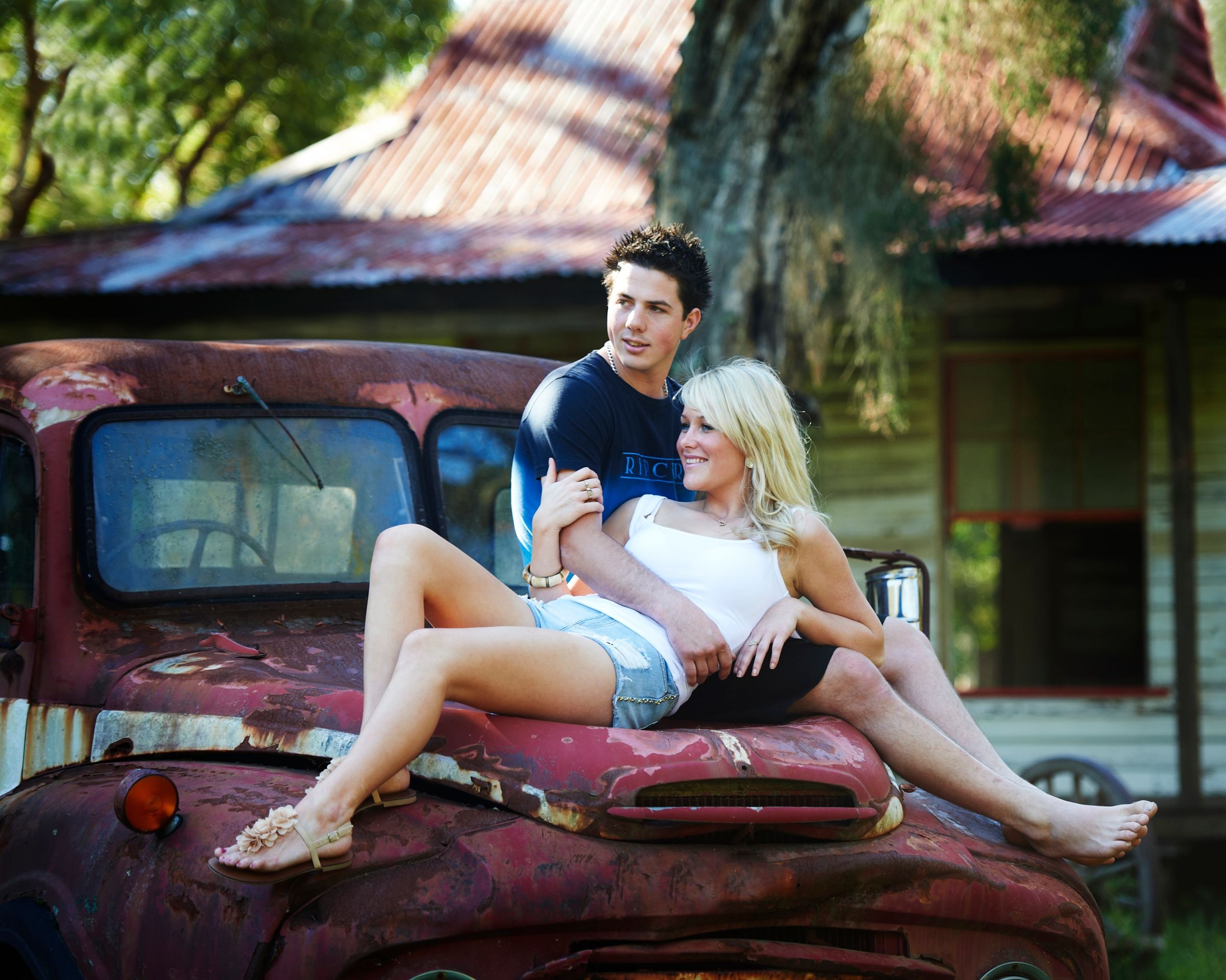 A young couple lying back on the bonnet of the red truck