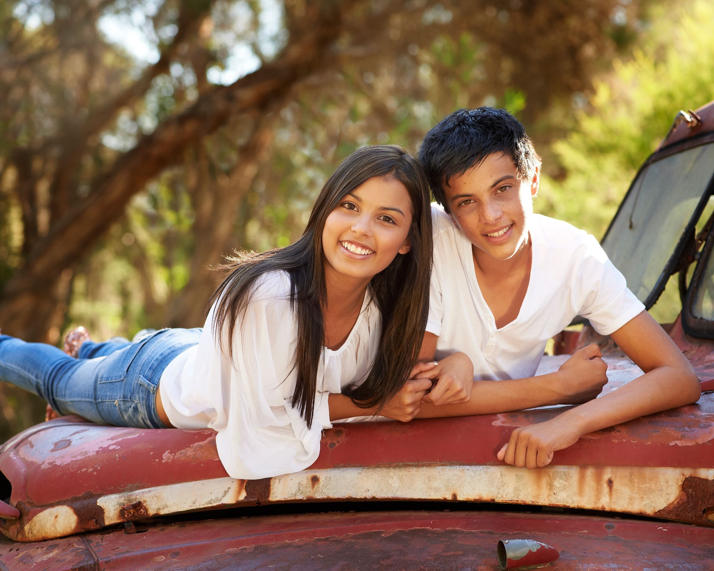 A brother and sister lying on the bonnet of the red truck