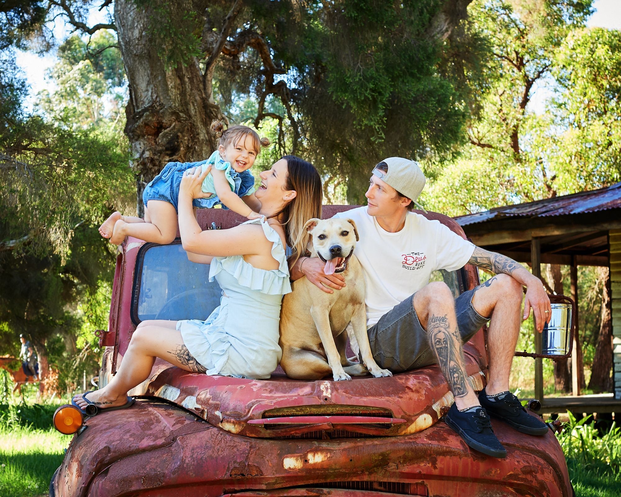 A family and their dog sitting on the bonnet of the red truck
