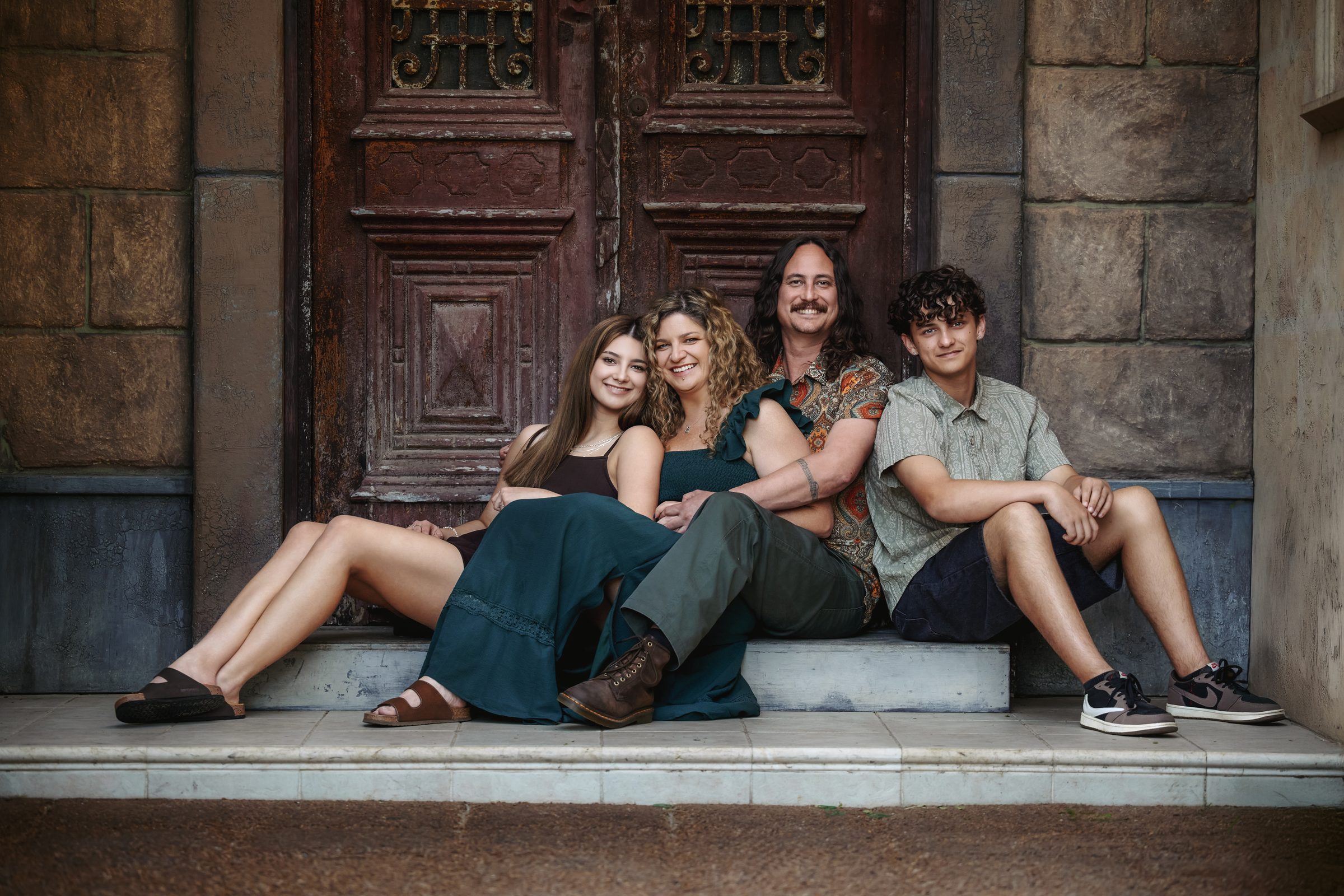 A family of four sitting close together on the steps of the Egyptian Doors