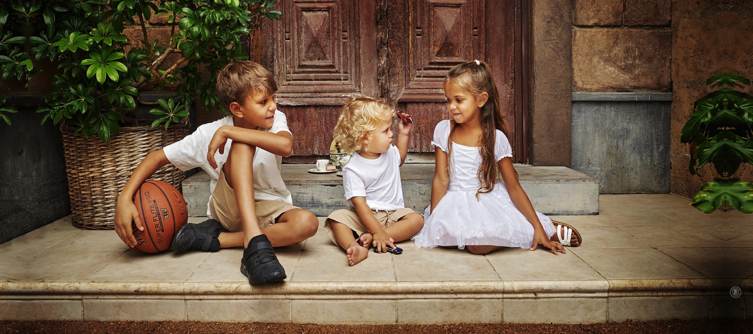 Three children sitting on the steps of the Egyptian Doors at Premier Studio