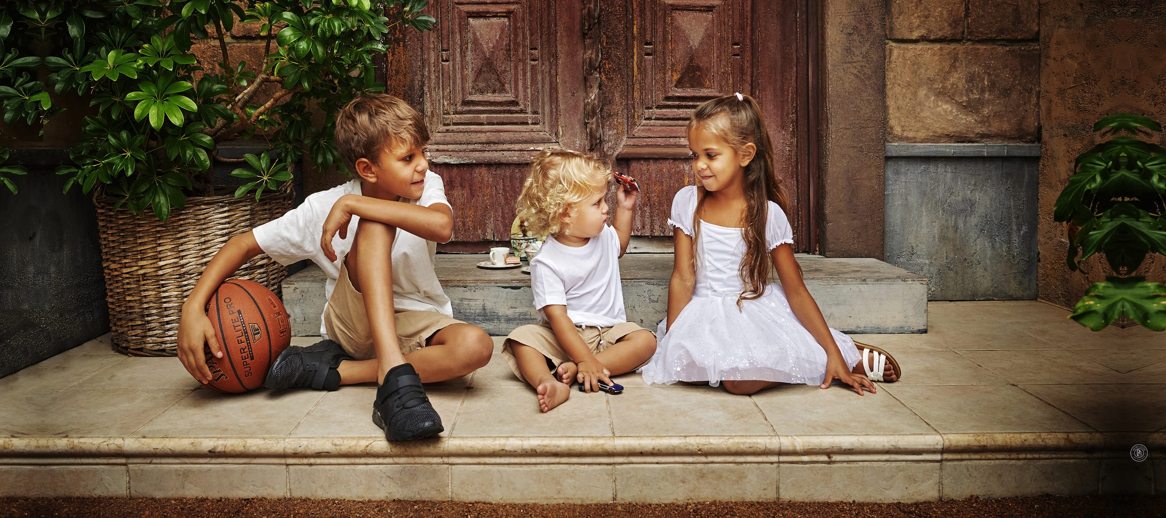 Three children sitting on the steps of the Egyptian Doors at Premier Studio