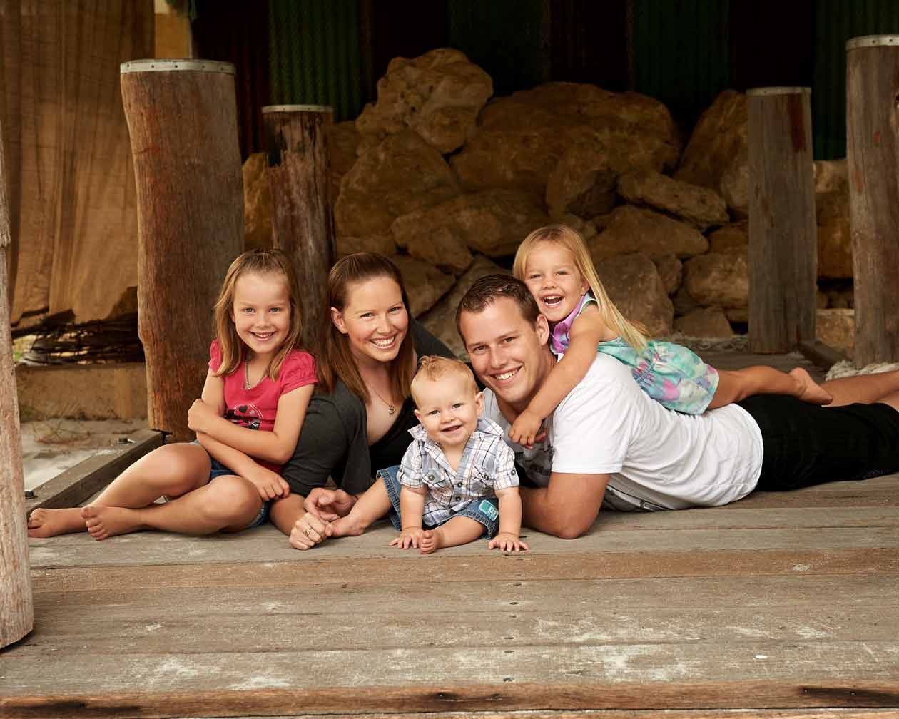A family of five lying together on the timber floor of the shed