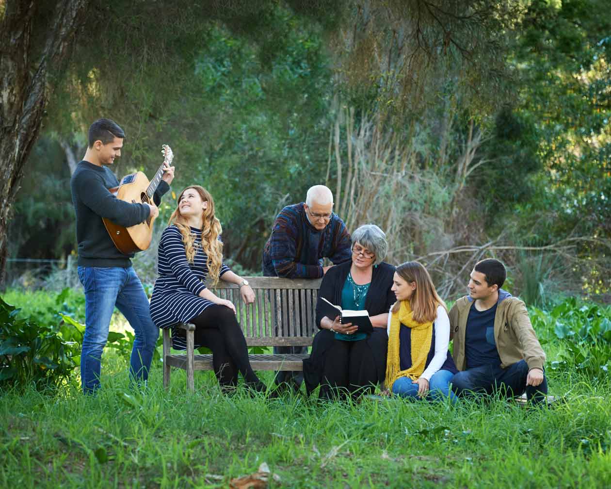 Three generations of a family relaxing around a garden bench