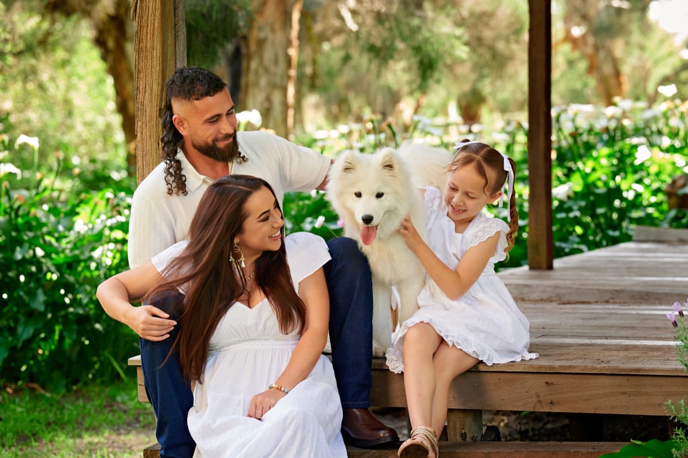 A family and their white dog on a timber verandah
