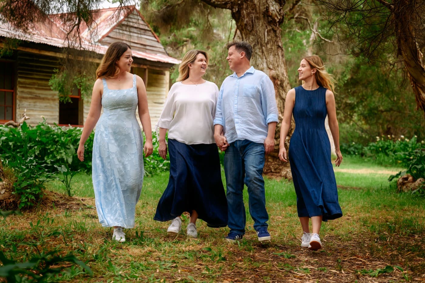 A family of four walking together past a timber hut
