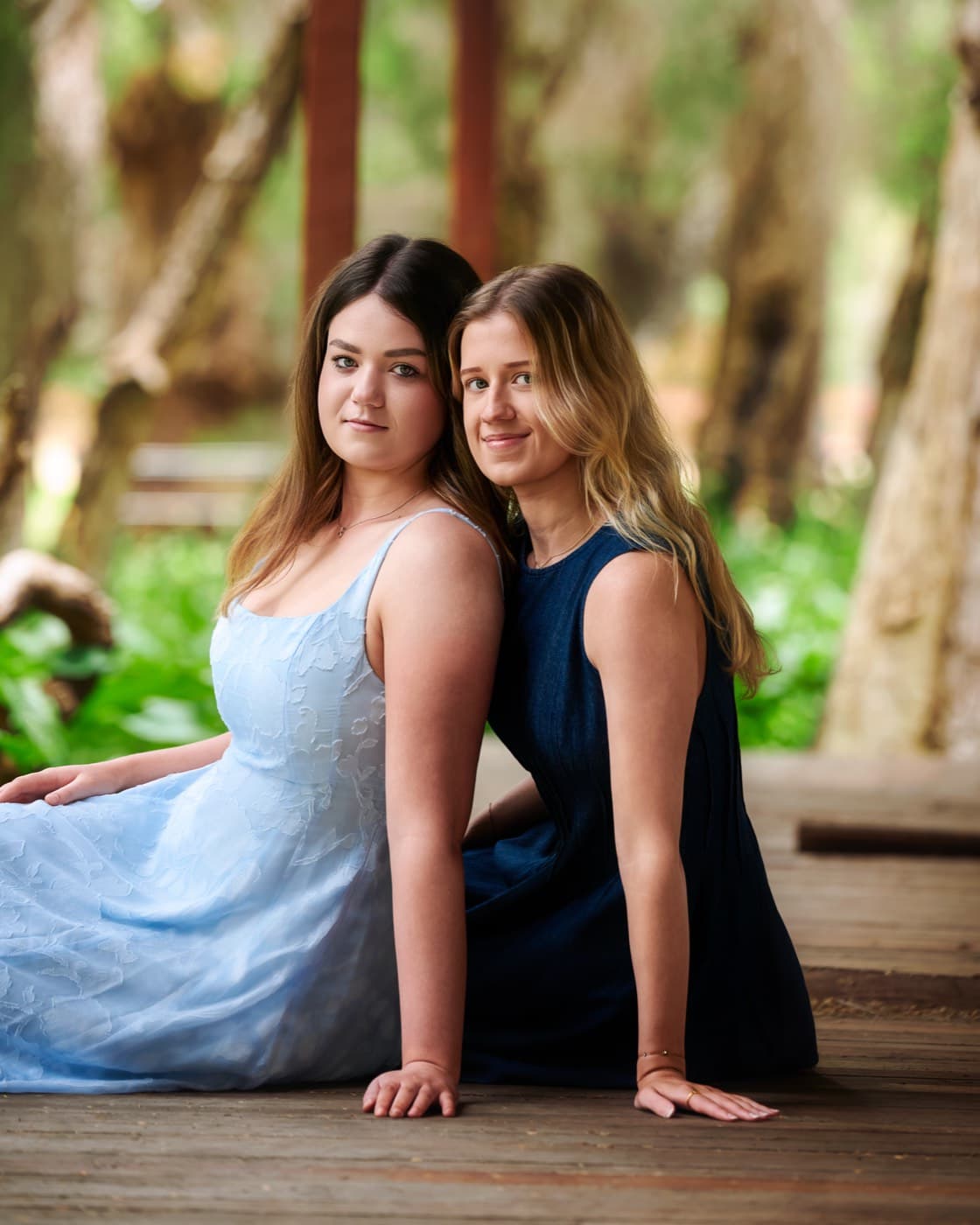 Two sisters sitting together on a timber deck