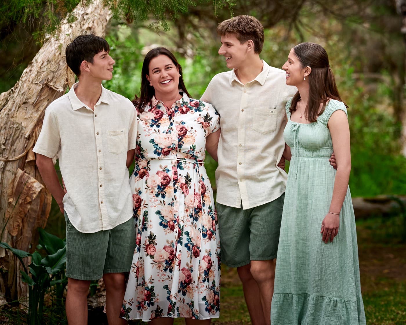 A family of four standing together among the trees