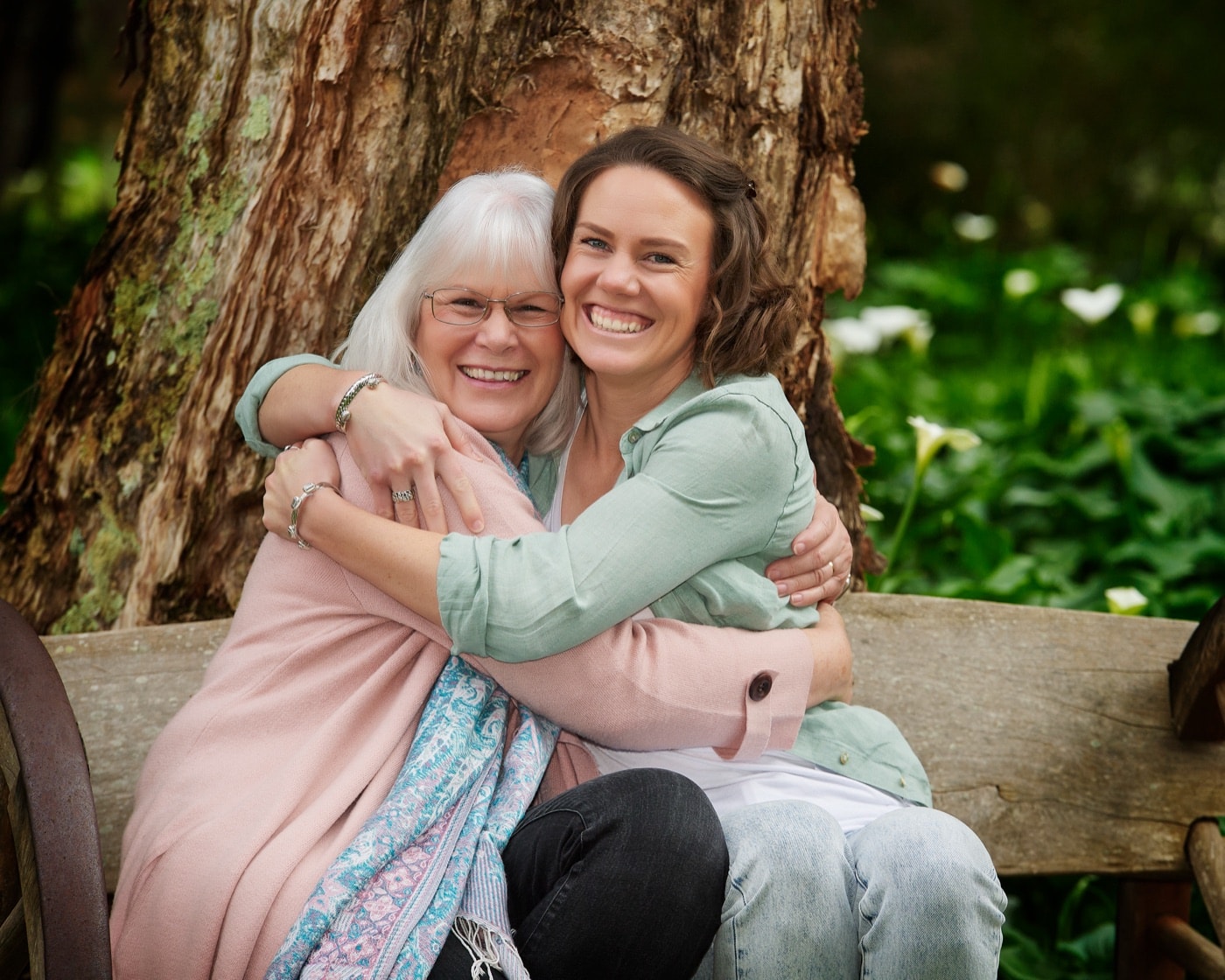 A grandmother and her daughter hugging on a bench