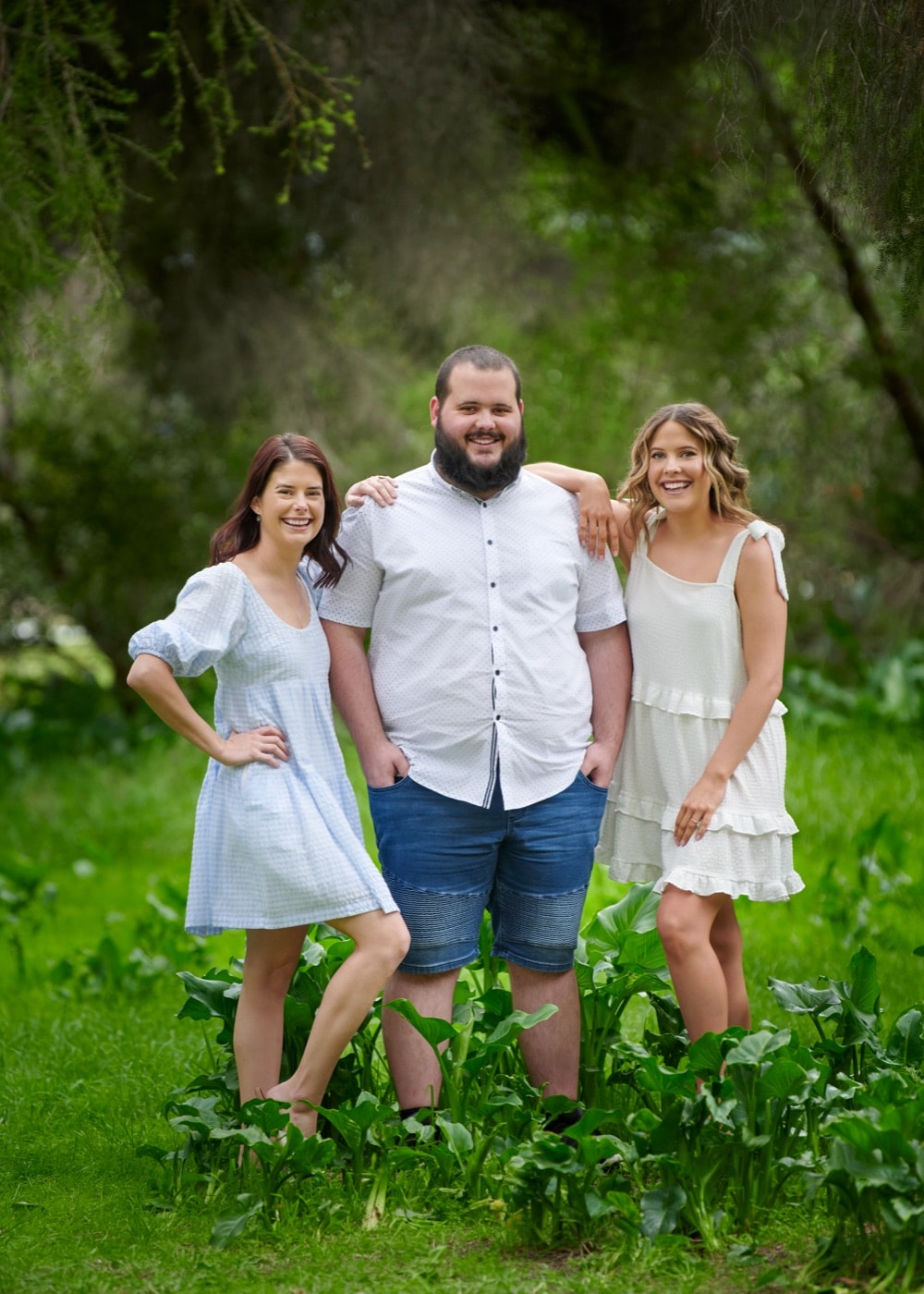 Three grown siblings standing among the lilies