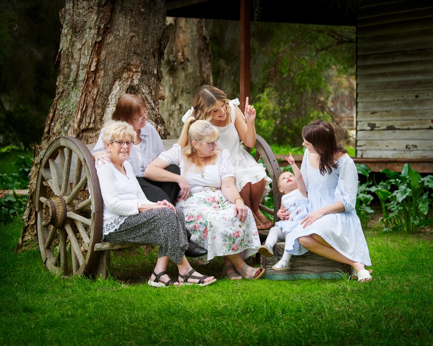 A grandmother with her daughters and grandchildren by the wagon wheel