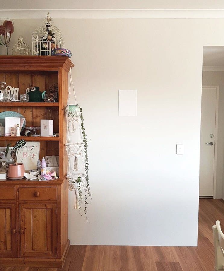 A blank wall beside a pine bookcase, with an A4 sheet of paper taped to it for scale