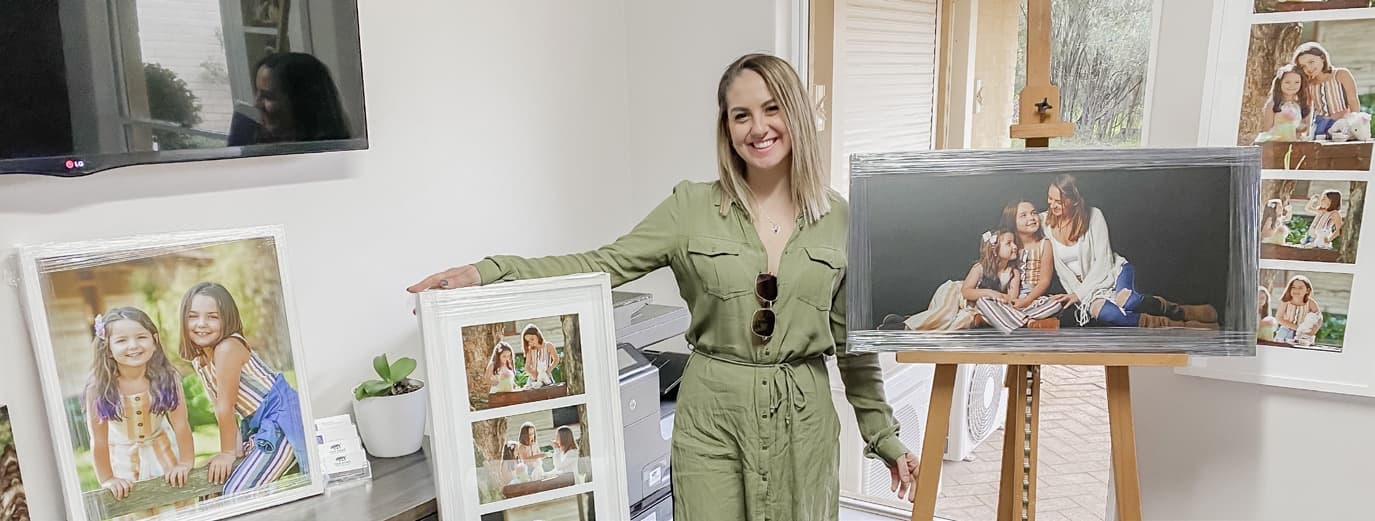 Jonelle in the studio with framed portraits and a large canvas on an easel