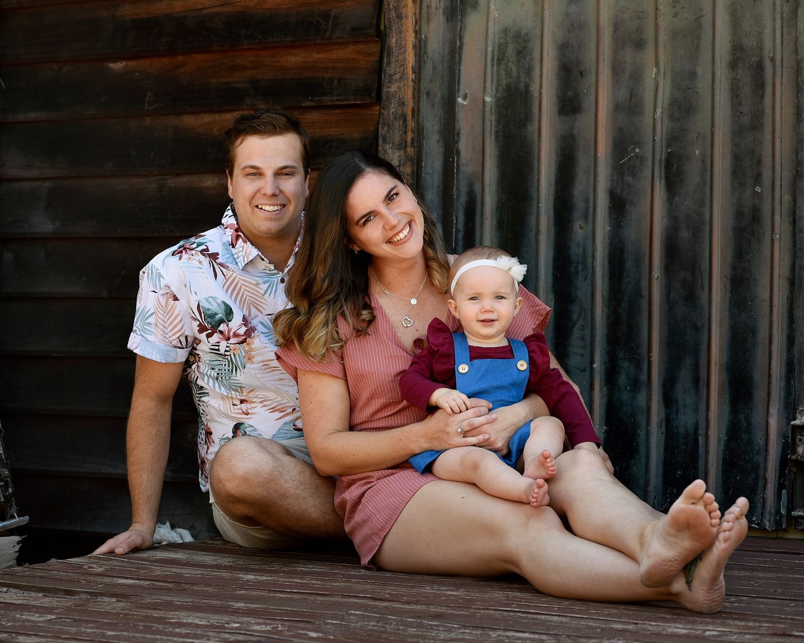A young couple sitting on the boards with their baby