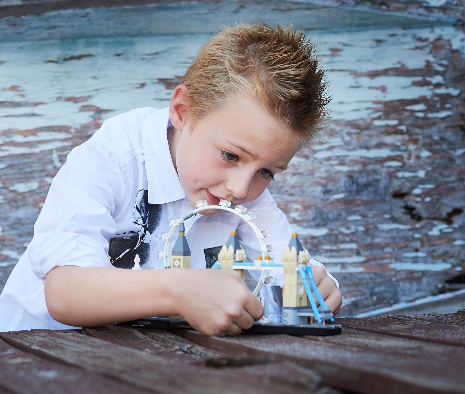 A boy building a toy model on the weathered timber