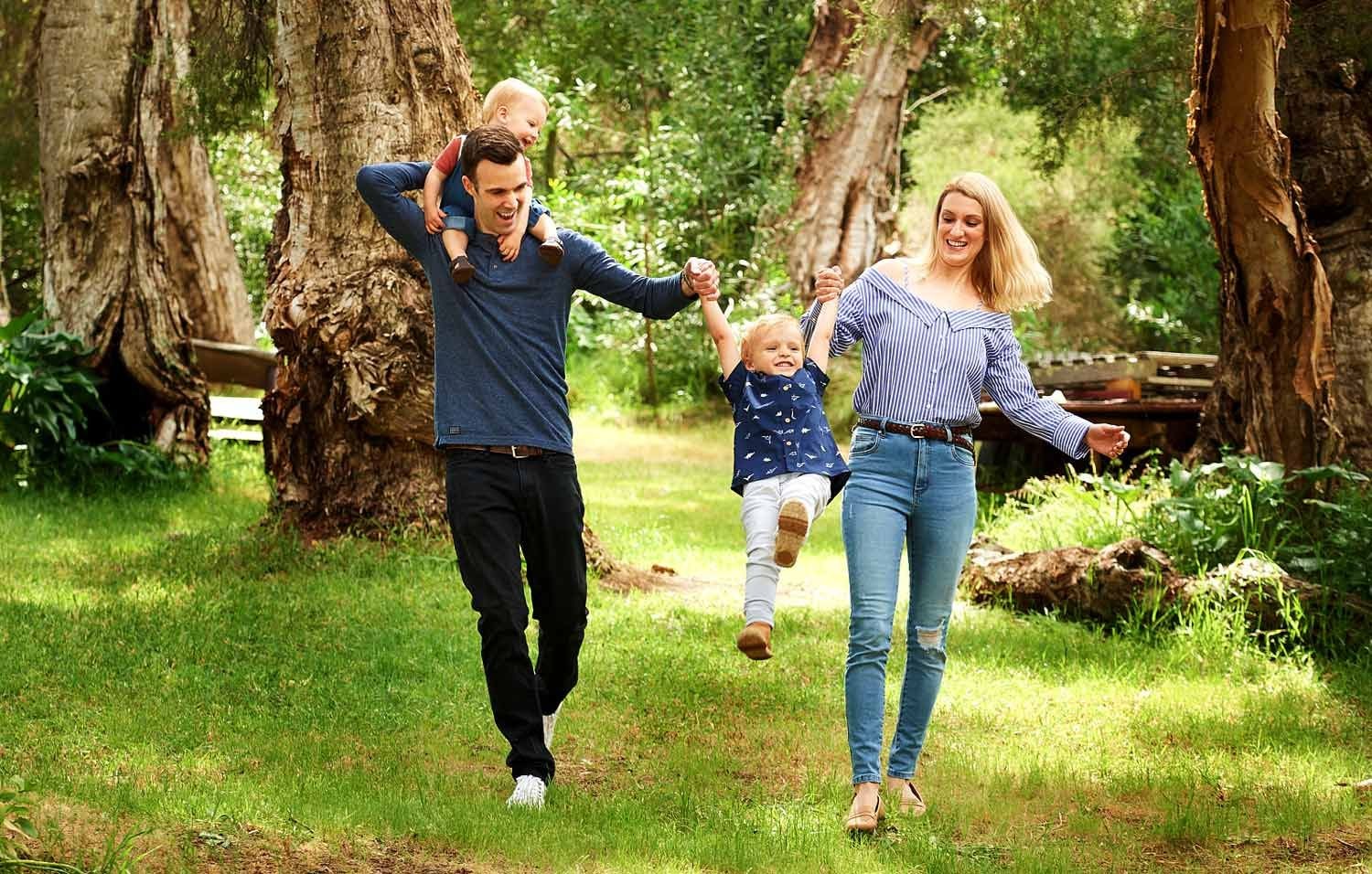 Parents swinging their toddler between them along a bushland path