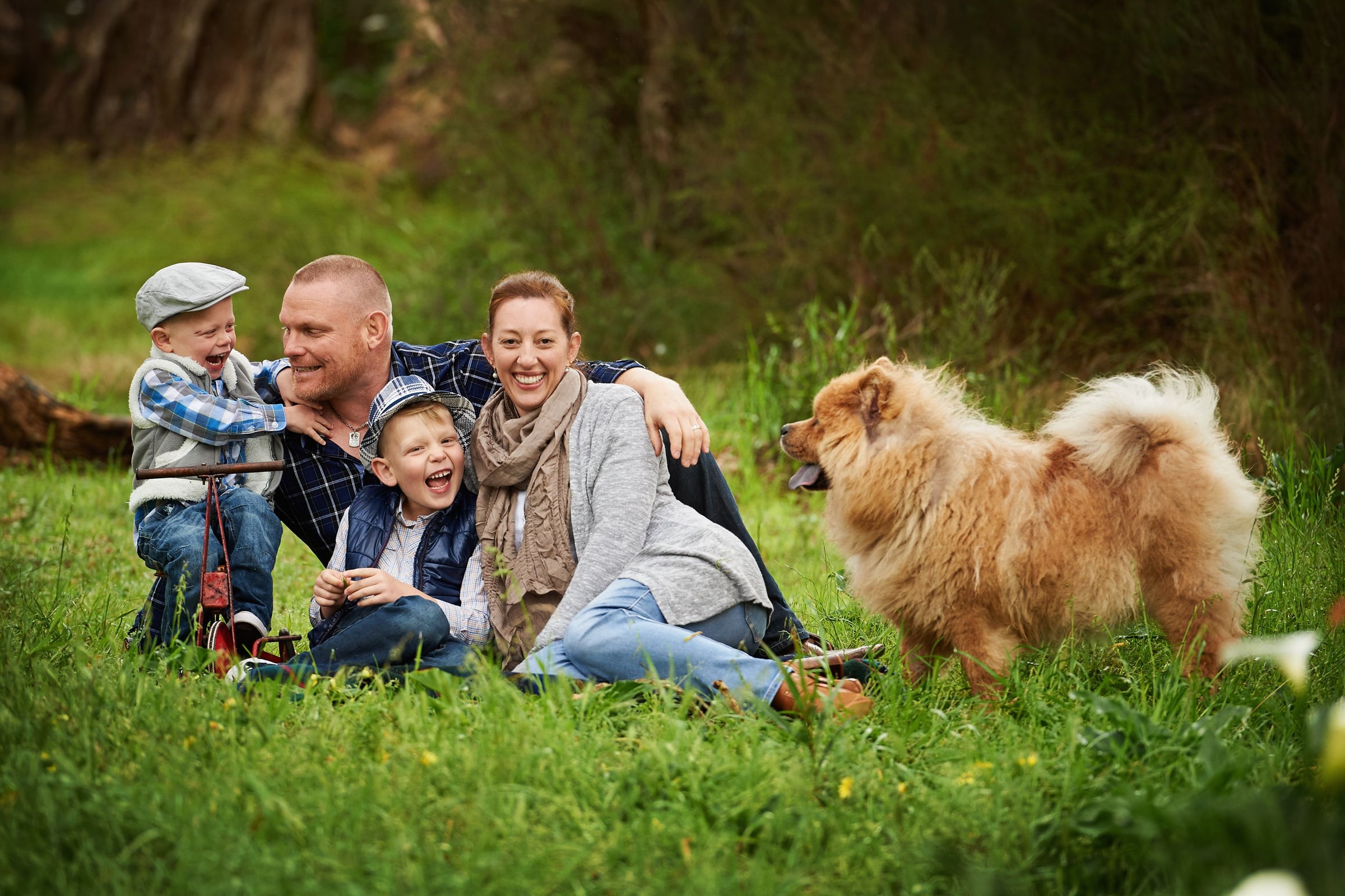 A family relaxing on the grass with their fluffy dog