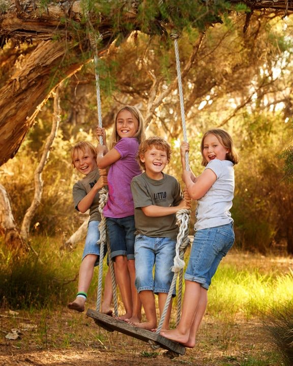 Four children squeezed together on the tree swing