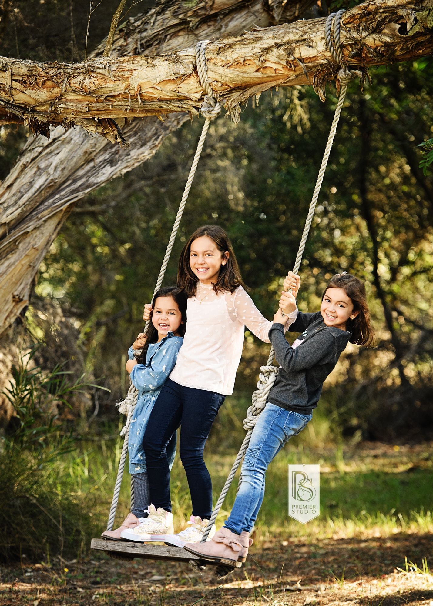 Three sisters standing together on the tree swing