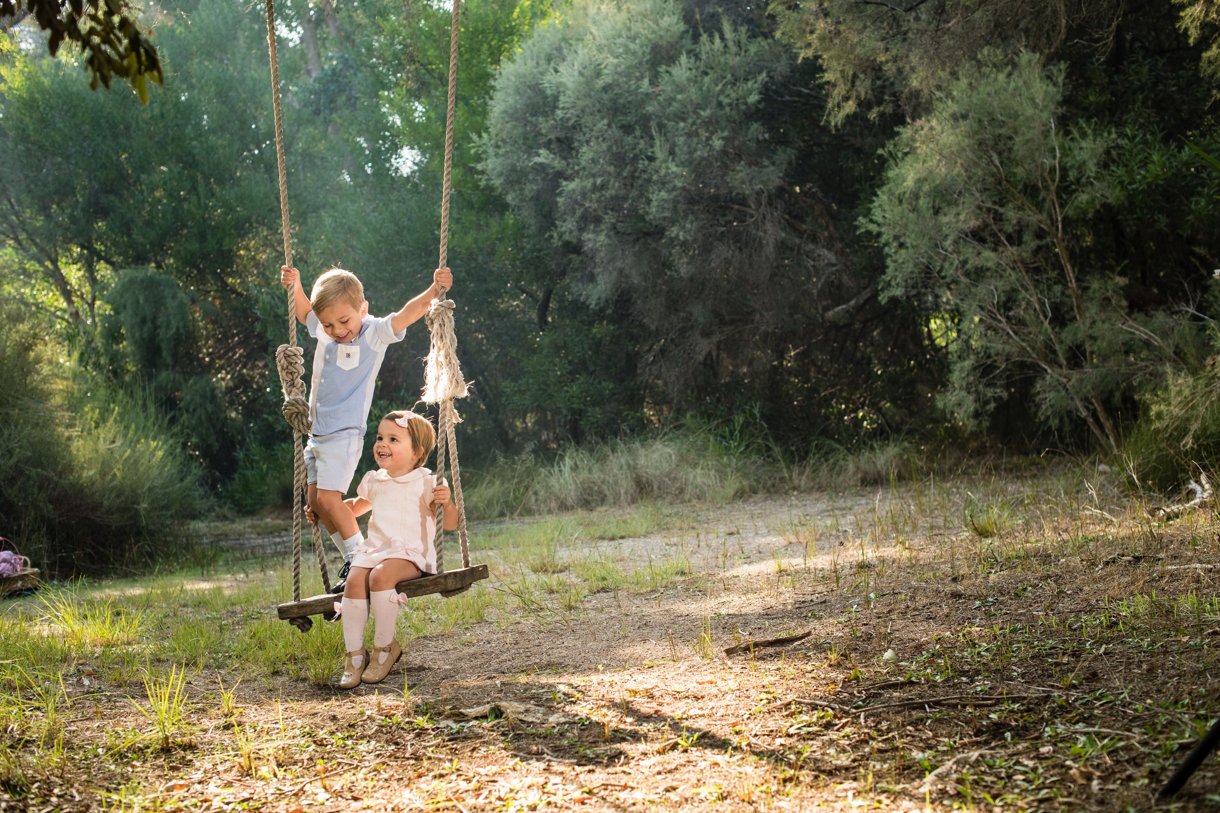 Two children on the swing in a bushland clearing