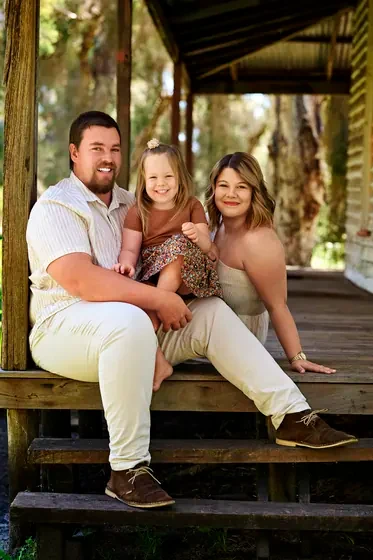 Parents in cream with their daughter in caramel and floral on the veranda steps at Premier Studio