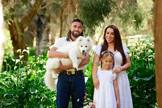 Family in white with dad in denim holding their Samoyed among the arum lilies at Premier Studio