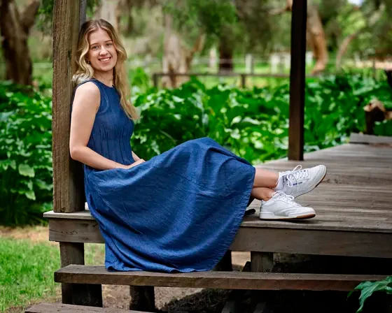 Young woman in a navy maxi dress seated on the timber deck at Premier Studio