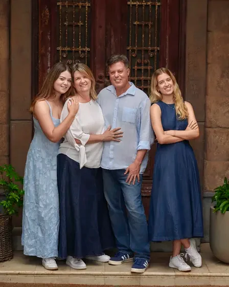 Family of four in chambray blue, navy and cream in front of the aged doors at Premier Studio