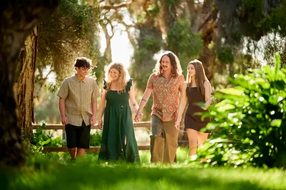 Family of four in emerald green, olive and black walking through the bush at Premier Studio