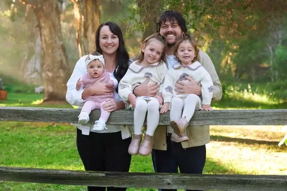 Parents in black with three little girls in cream and blush knits at the timber fence, Premier Studio