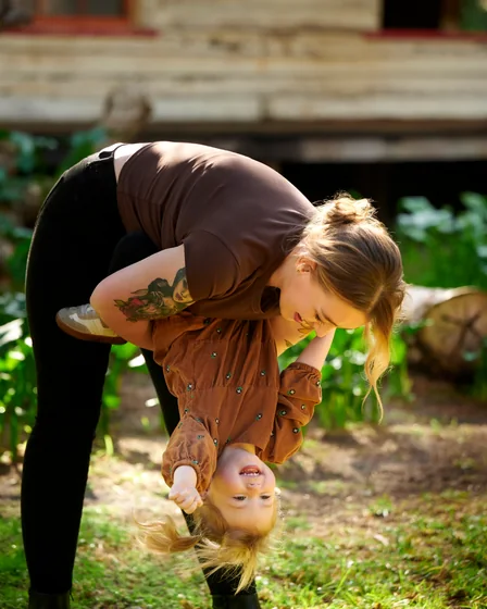 Mum in black swinging her daughter in a chocolate brown dress at Premier Studio