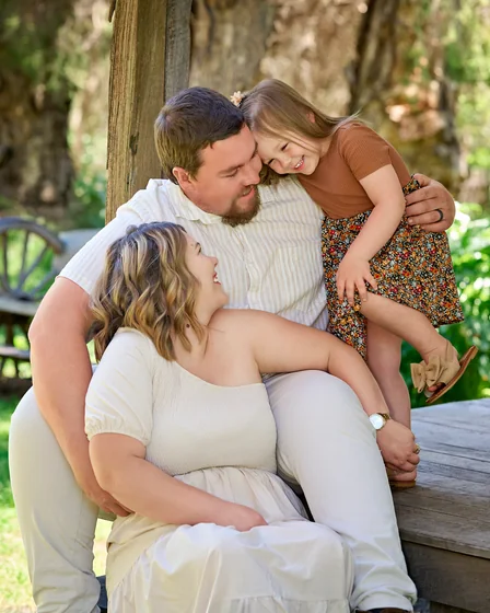 Parents in cream with their daughter in a caramel top and floral skirt on the veranda at Premier Studio