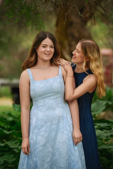 Two sisters in powder blue and navy dresses standing in the garden at Premier Studio