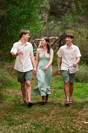 Mum in sage green with two teenage sons in cream shirts and olive shorts walking through the bush at Premier Studio