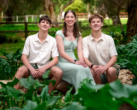 Mum in sage green with two teenage sons in cream seated among the lilies at Premier Studio