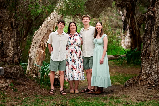 Family of four in sage, cream and a soft floral dress beneath the paperbark trees at Premier Studio
