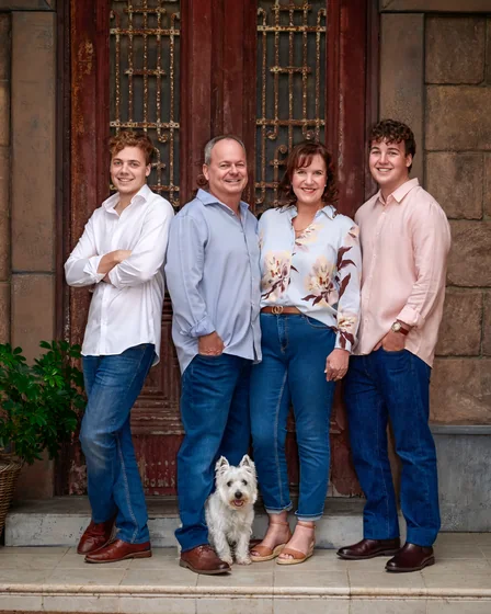 Family of four in navy, light blue and cream florals with their terrier at the red doors at Premier Studio