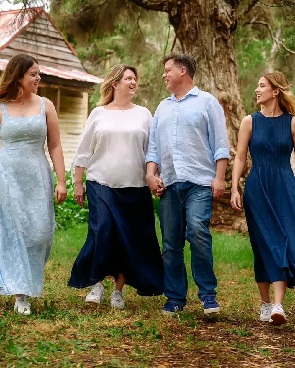 Family of four in light blue, navy and cream walking past the cottage at Premier Studio