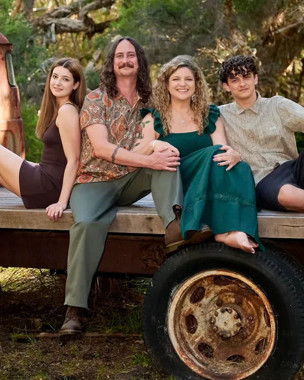 Family of four in dark teal, olive and black seated on the flatbed truck at Premier Studio