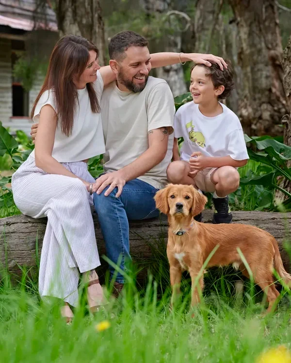 Parents in cream and denim with their son and puppy on a fallen log at Premier Studio