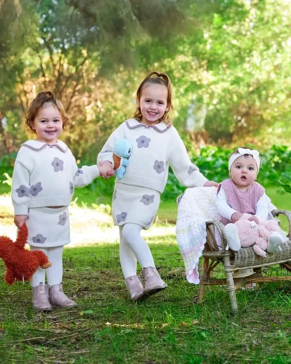 Three sisters in pink and cream outfits walking through the garden at Premier Studio